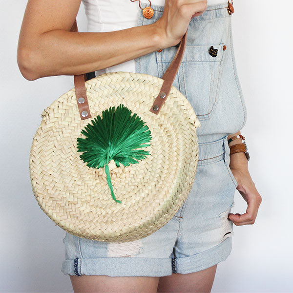 Raffia embroidery on a round bag made of plaited straw
