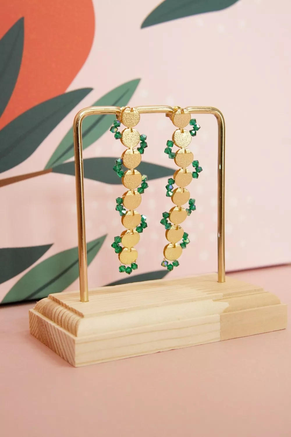 Long gold earrings with green crystal spinning tops