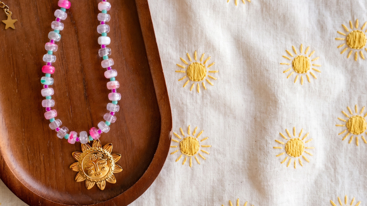Collier perles rondelles en résine et pendentif soleil Collier perles rondelles en résine et pendentif soleil